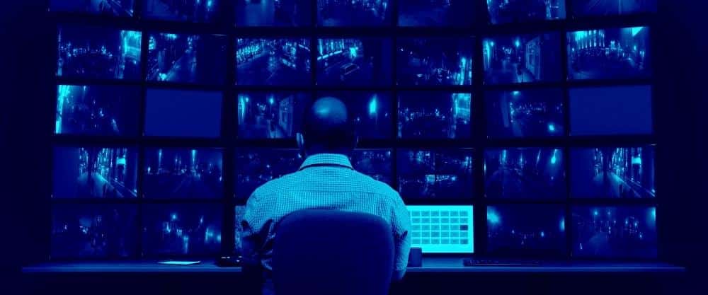 A man in front of many screens representing the work of a private detective - OGEN